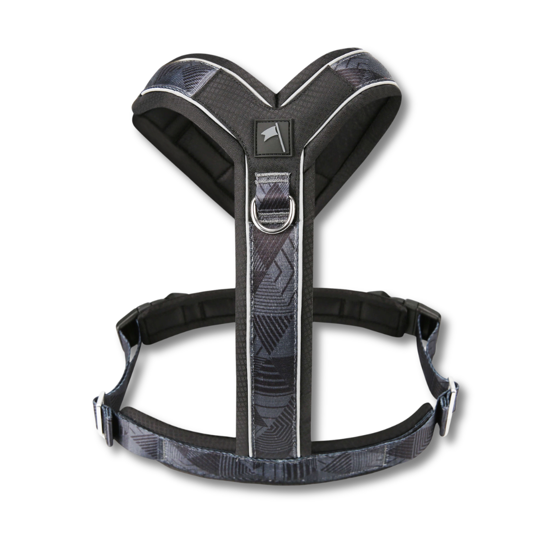A dog harness with a black and gray geometric pattern, featuring padded black shoulder and belly sections with silver metal hardware, shown against a plain white background.