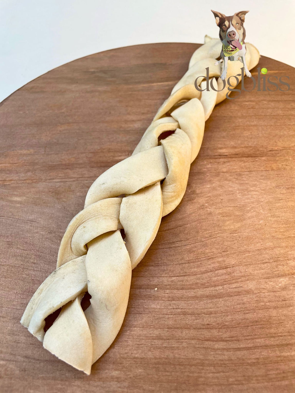 Braided dog toy on a wooden surface with a dog in the background