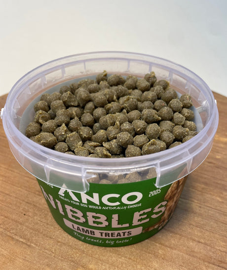 Container of dog treats with a visible brand label on a wooden surface.