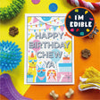 A colorful pet birthday card reading 'HAPPY BIRTHDAY CHEW YA' is displayed on a bright yellow and orange background with dog treats, dog toys, and a circular badge that says 'I'M EDIBLE'.