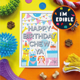 A colorful pet birthday card reading 'HAPPY BIRTHDAY CHEW YA' is displayed on a bright yellow and orange background with dog treats, dog toys, and a circular badge that says 'I'M EDIBLE'.