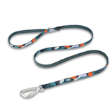 A dog leash with a dark teal-green base and an abstract geometric pattern in orange, light blue, and white. It features a silver metal carabiner clip on one end and a quick-release buckle on the other, displayed on a clean white background.