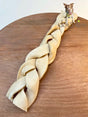 Braided dog toy on a wooden surface with a dog in the background